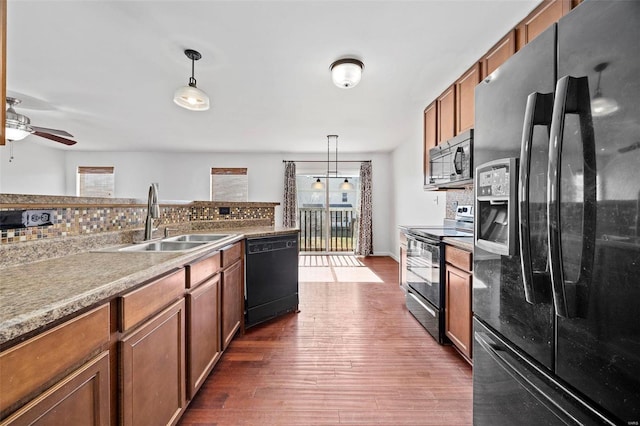 kitchen with black appliances, brown cabinetry, a sink, and a wealth of natural light