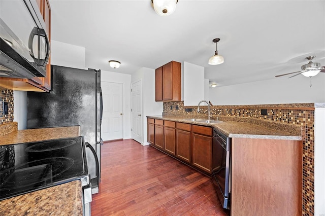 kitchen featuring a peninsula, dark wood-type flooring, a sink, brown cabinets, and black appliances