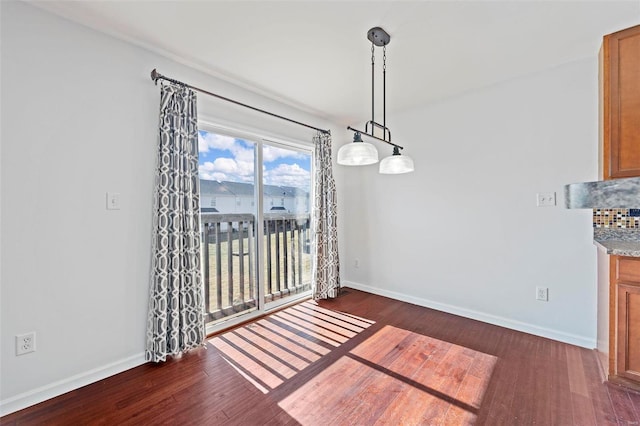 unfurnished dining area featuring wood finished floors and baseboards