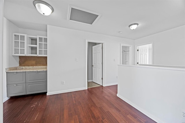 unfurnished dining area featuring dark wood-style floors, attic access, and baseboards