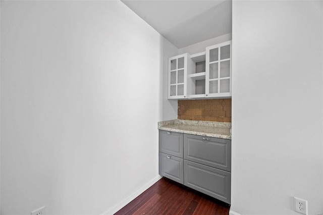 interior space with tasteful backsplash, baseboards, dark wood-style floors, light stone countertops, and gray cabinets