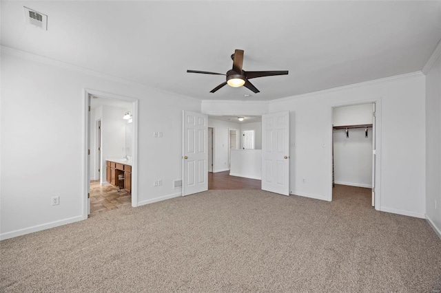 unfurnished bedroom with baseboards, visible vents, carpet, a spacious closet, and crown molding