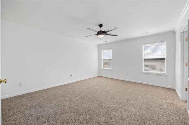 carpeted spare room featuring crown molding, ceiling fan, and baseboards