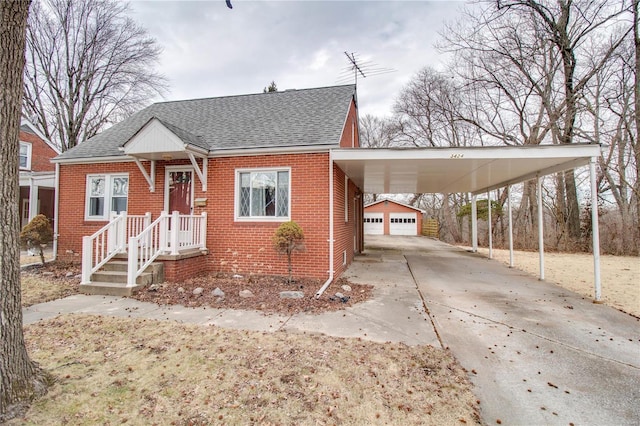 bungalow featuring a garage, brick siding, an outdoor structure, and a shingled roof