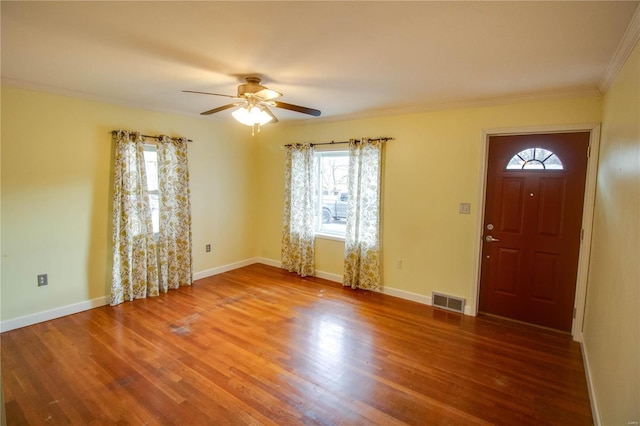 foyer entrance with wood finished floors, a ceiling fan, visible vents, baseboards, and ornamental molding