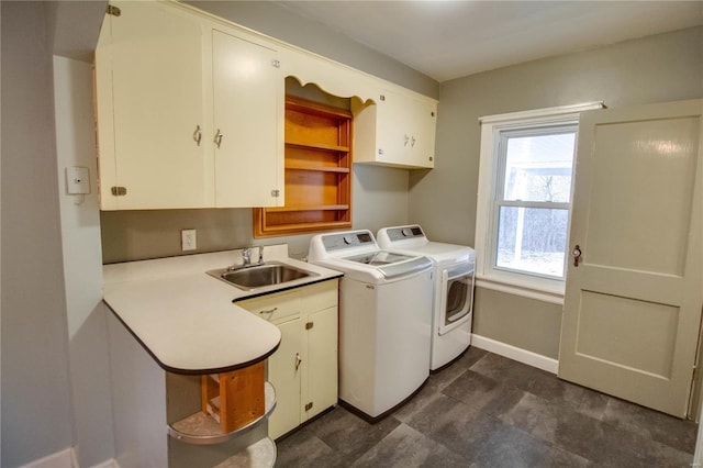 washroom with washer and clothes dryer, a sink, cabinet space, and baseboards