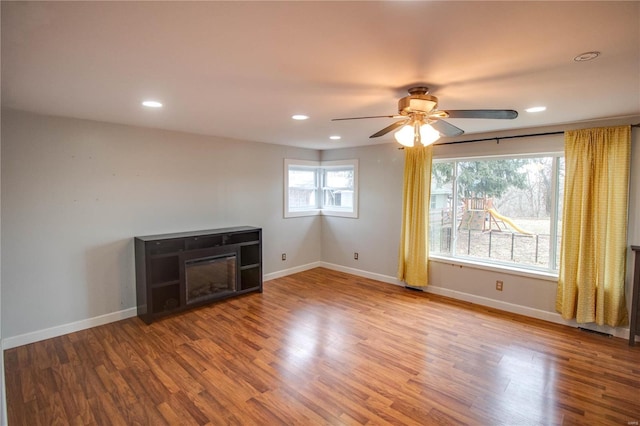 unfurnished living room featuring recessed lighting, a fireplace, wood finished floors, and baseboards