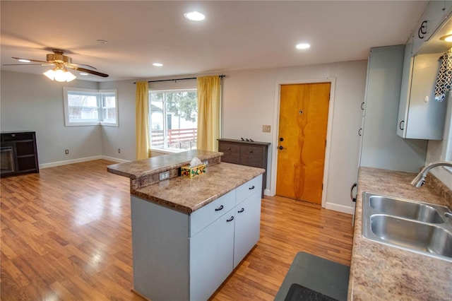 kitchen with recessed lighting, baseboards, a sink, and light wood finished floors