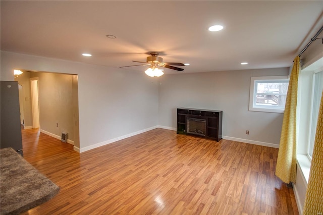 unfurnished living room featuring baseboards, visible vents, ceiling fan, and wood finished floors