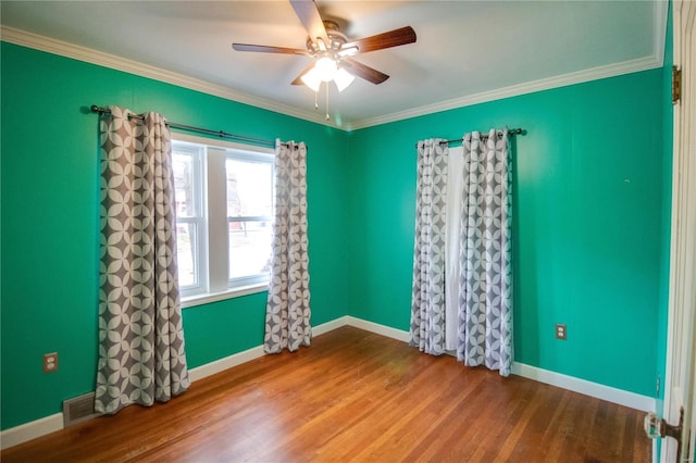 spare room with visible vents, crown molding, baseboards, and wood finished floors