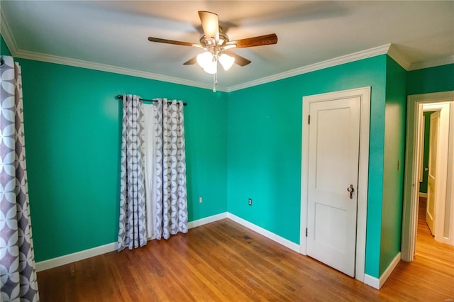 spare room featuring baseboards, wood finished floors, a ceiling fan, and crown molding