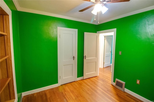 unfurnished bedroom with baseboards, visible vents, ceiling fan, crown molding, and light wood-type flooring