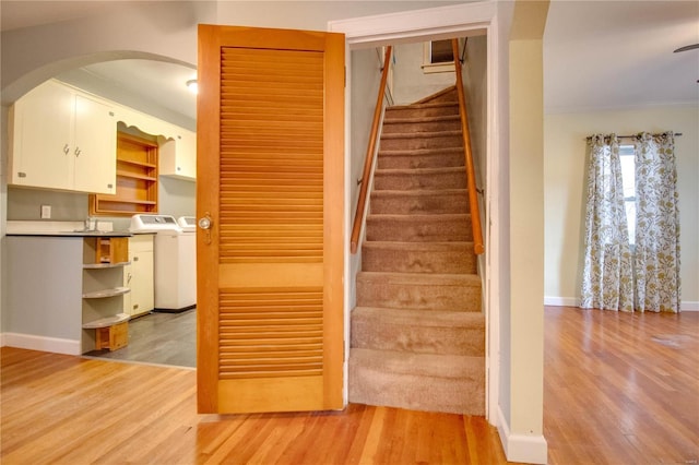 stairway featuring arched walkways, crown molding, baseboards, and wood finished floors