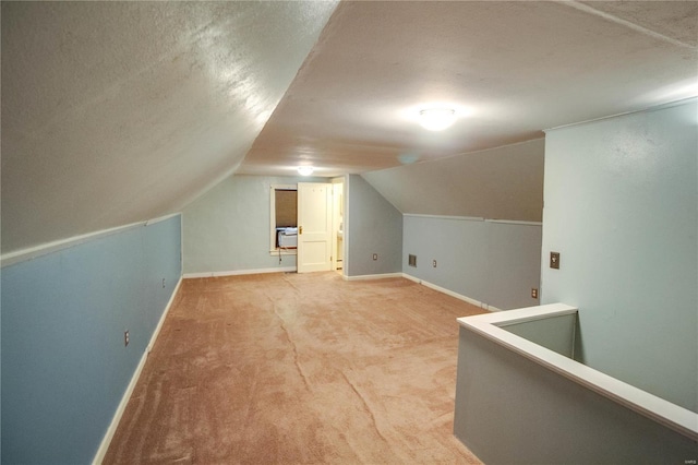 additional living space with lofted ceiling, a textured ceiling, light carpet, and baseboards