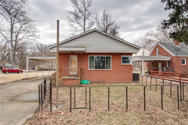 bungalow-style house featuring concrete driveway, a fenced front yard, a gate, a carport, and brick siding