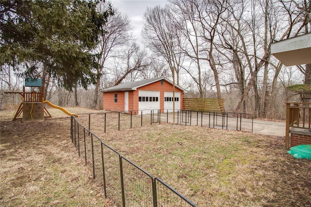 view of yard with an outbuilding, a playground, fence, and a garage