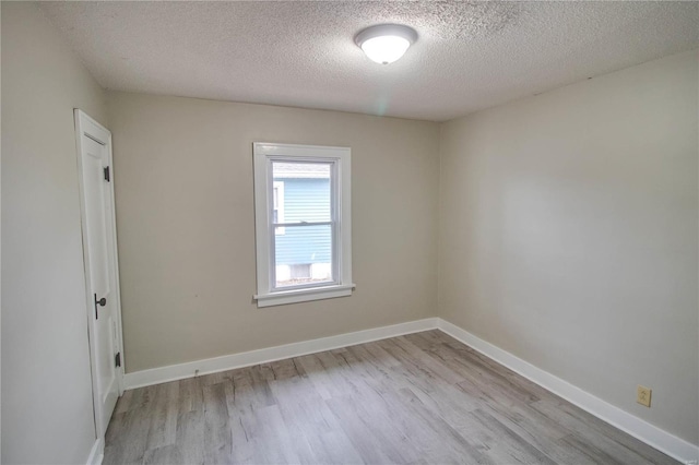 unfurnished room with light wood-style flooring, baseboards, and a textured ceiling