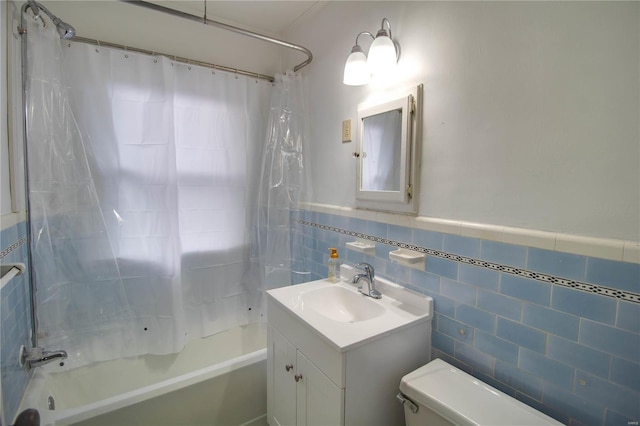 full bath featuring toilet, a wainscoted wall, shower / bath combo with shower curtain, vanity, and tile walls