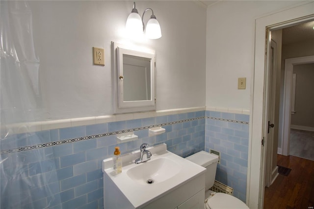 bathroom featuring wainscoting, tile walls, wood finished floors, and vanity