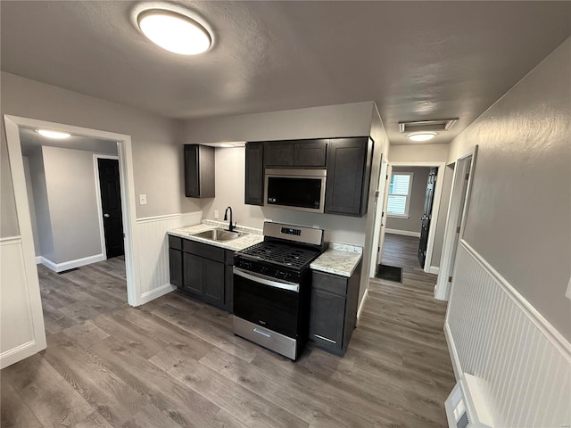 kitchen featuring stainless steel appliances, light countertops, a sink, and light wood finished floors