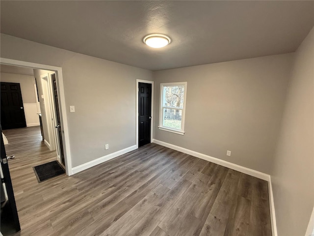 unfurnished bedroom with wood finished floors and baseboards