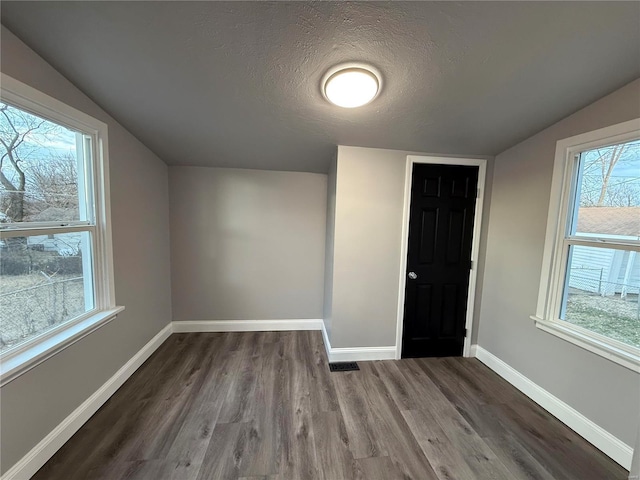 bonus room featuring visible vents, vaulted ceiling, a textured ceiling, wood finished floors, and baseboards