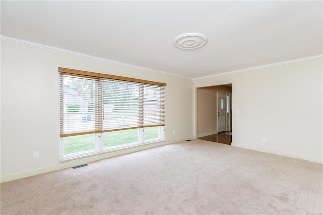 spare room with carpet floors, baseboards, visible vents, and crown molding