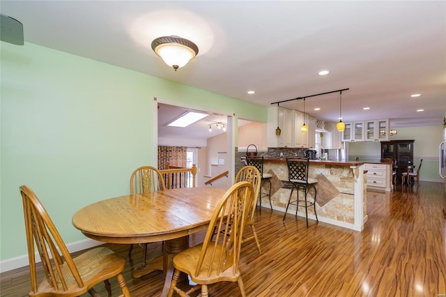 dining room featuring baseboards, wood finished floors, and recessed lighting