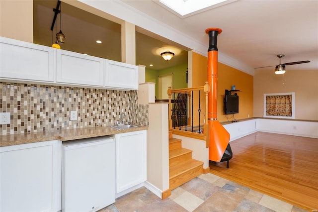 kitchen featuring lofted ceiling, ceiling fan, backsplash, white cabinetry, and a sink