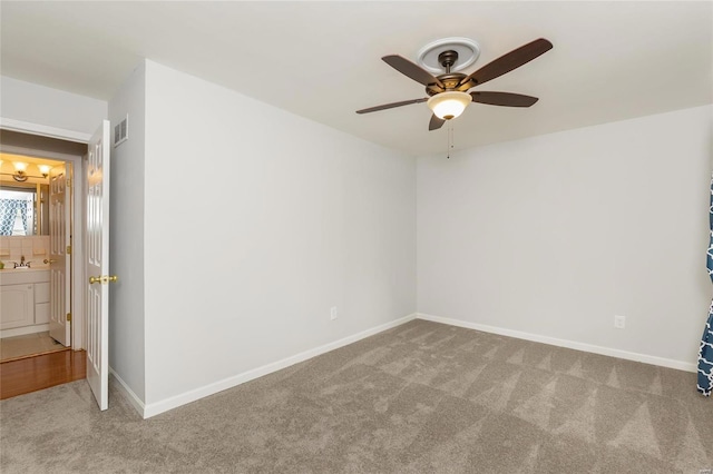 carpeted spare room with visible vents, ceiling fan, a sink, and baseboards