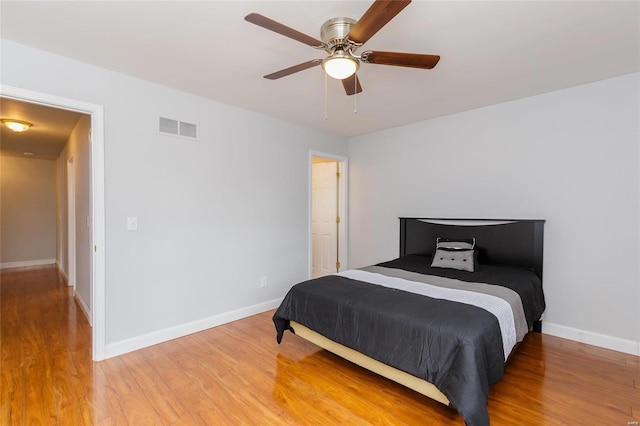 bedroom with ceiling fan, light wood-style flooring, visible vents, and baseboards