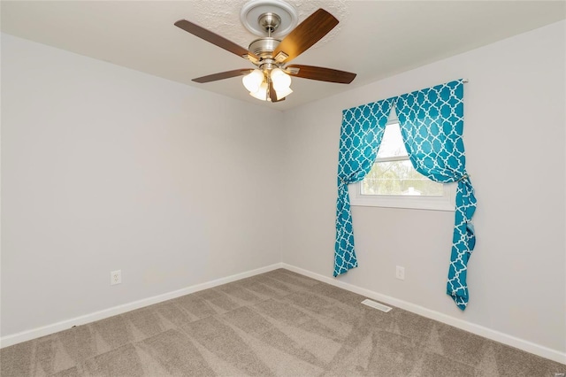 unfurnished room with carpet floors, visible vents, baseboards, and a ceiling fan