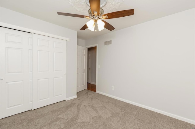 unfurnished bedroom featuring visible vents, baseboards, ceiling fan, carpet, and a closet