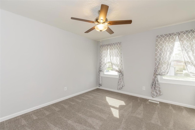 carpeted spare room with ceiling fan and baseboards