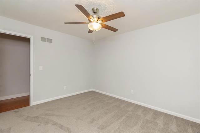 empty room with a ceiling fan, carpet, visible vents, and baseboards