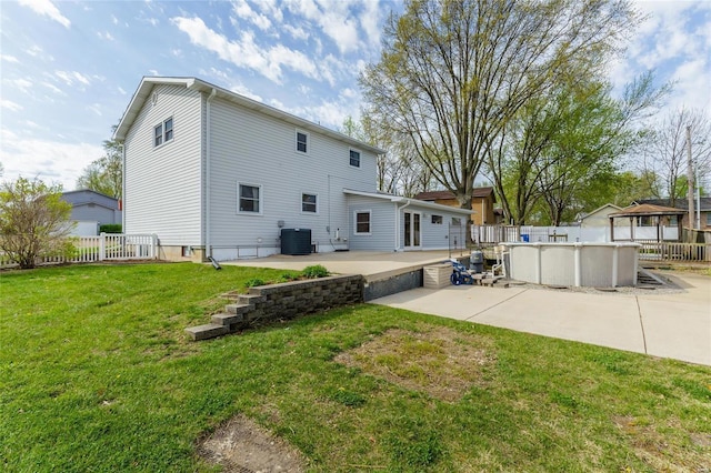 rear view of property featuring a yard, a patio, fence, cooling unit, and an outdoor pool