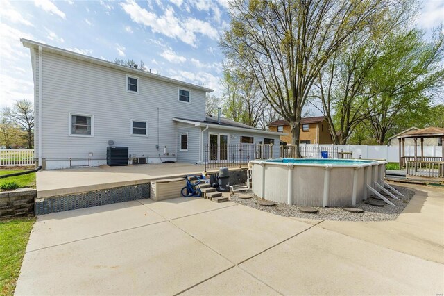 rear view of property featuring a patio, central AC, fence, a gazebo, and a fenced in pool