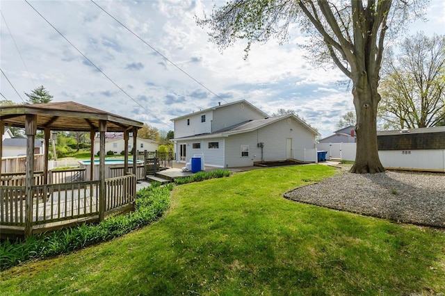 back of property with a deck, fence, a gazebo, a lawn, and a fenced in pool