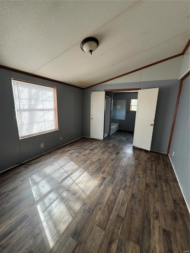 unfurnished bedroom with lofted ceiling, dark wood-style flooring, a textured ceiling, crown molding, and a closet