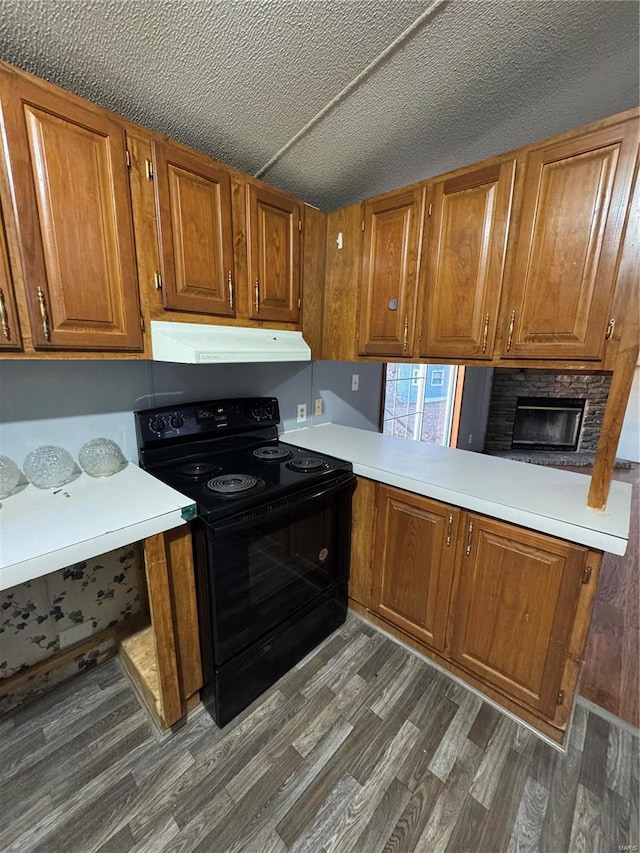 kitchen with brown cabinets, dark wood finished floors, light countertops, under cabinet range hood, and black / electric stove