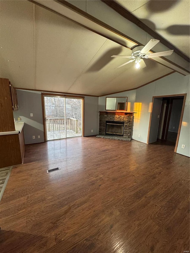 unfurnished living room featuring lofted ceiling with beams, visible vents, dark wood-style flooring, and a stone fireplace