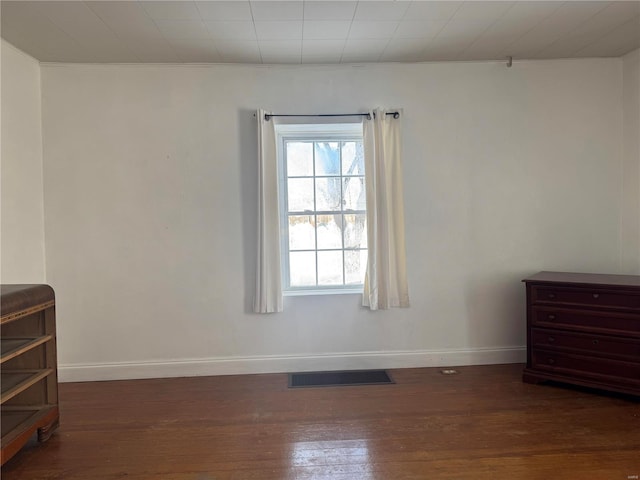 empty room with baseboards, visible vents, and dark wood-type flooring