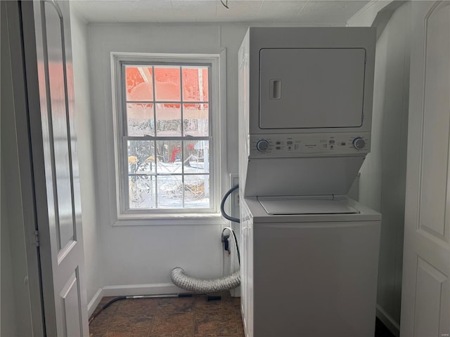 laundry room with stacked washer / drying machine, laundry area, and baseboards