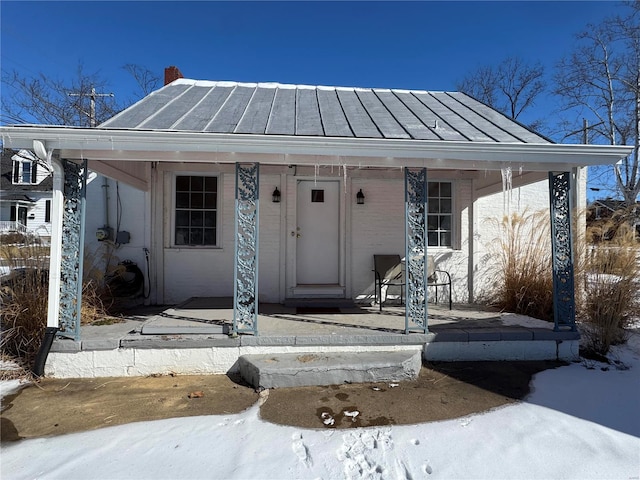 snow covered property entrance featuring metal roof and a standing seam roof