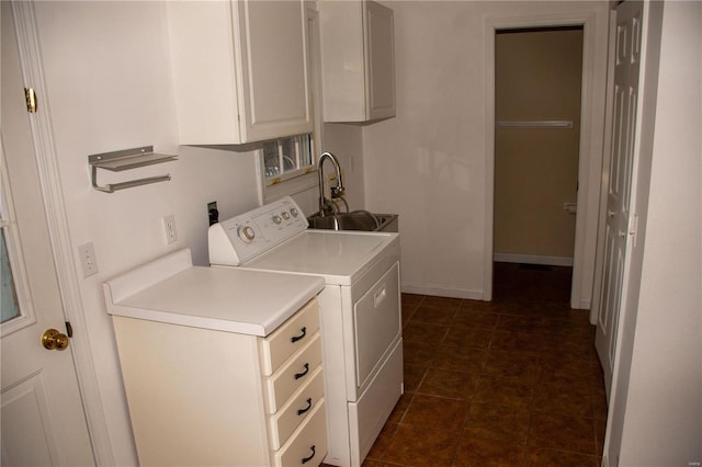 laundry room with separate washer and dryer, dark tile patterned floors, a sink, baseboards, and cabinet space