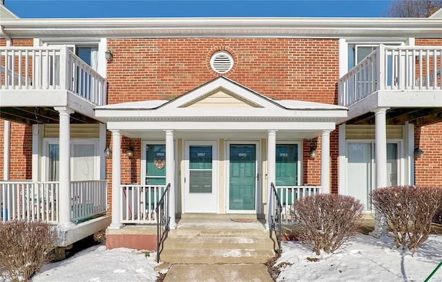 snow covered property entrance with brick siding