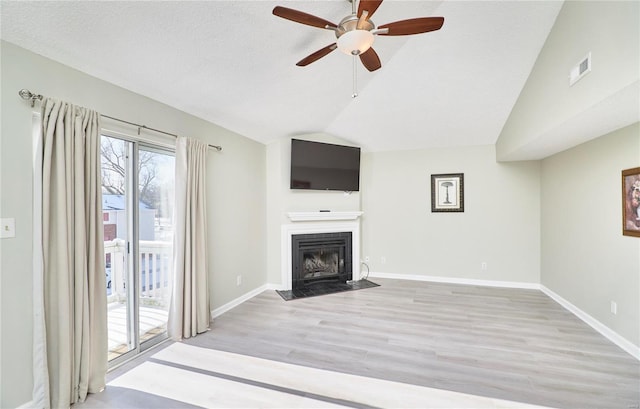 unfurnished living room with a fireplace with flush hearth, visible vents, baseboards, vaulted ceiling, and light wood-type flooring