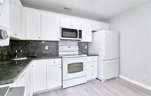 kitchen featuring white appliances, white cabinets, and a sink