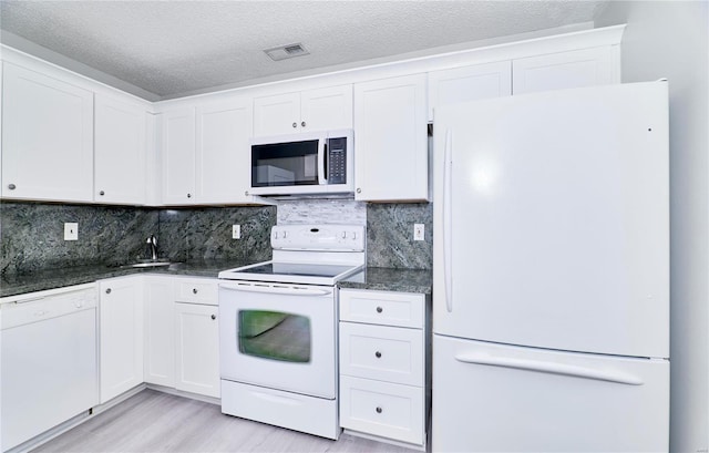 kitchen featuring visible vents, backsplash, white cabinetry, a sink, and white appliances