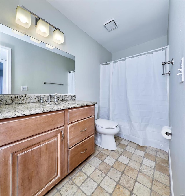 full bath with stone tile floors, vanity, and toilet